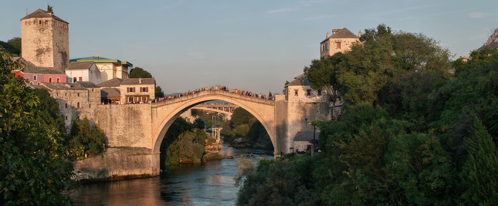 Divers lined up on the parapet of the Stari Most, the Neretva running turquoise beneath the Ottoman arch.